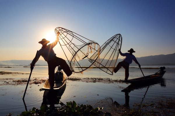 Die bekannten Einbeinfischer vom Inle Lake mit einem Fischernetz zum Sonnenuntergang - berühmt am Inle See.